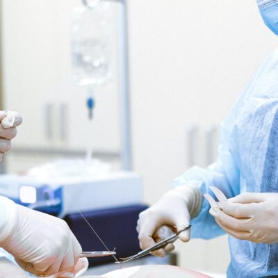 Principali complicazioni e profili di risarcimento danno sanitario Strumenti chirurgici in primo piano e chirurgo al lavoro in sala operatoria: assistenza legale per casi di malasanità e complicanze post-operatorie